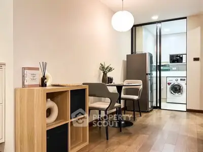 Modern dining area with stylish furniture and view into sleek kitchen with appliances.