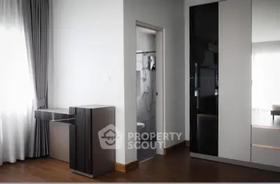 Modern bedroom with sleek wardrobe and open bathroom view, featuring elegant wooden flooring and natural light.