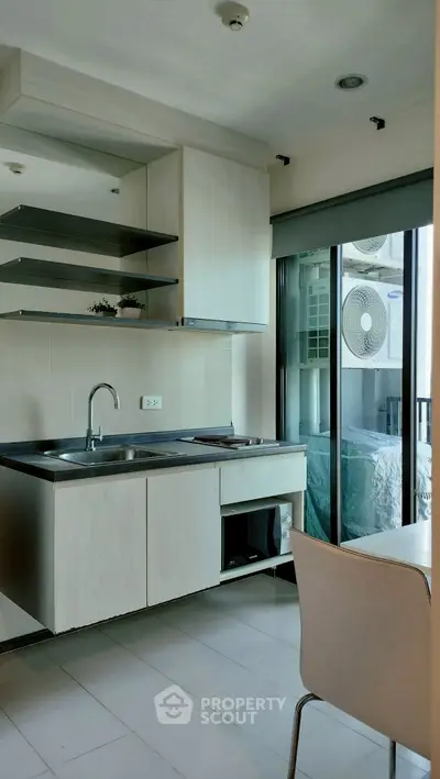 Modern kitchen with sleek cabinetry and large window offering natural light