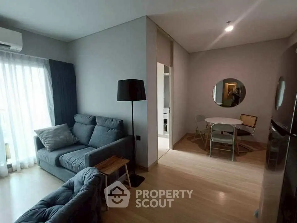 Modern living room with cozy seating and dining area, featuring natural light and stylish decor.