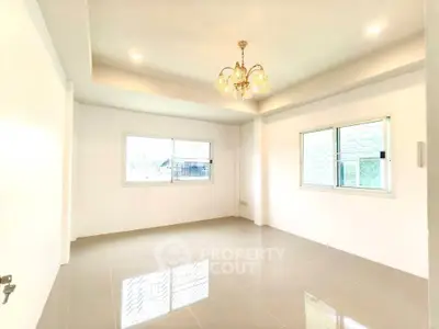 Bright and spacious empty room with elegant chandelier and large windows, perfect for customization.