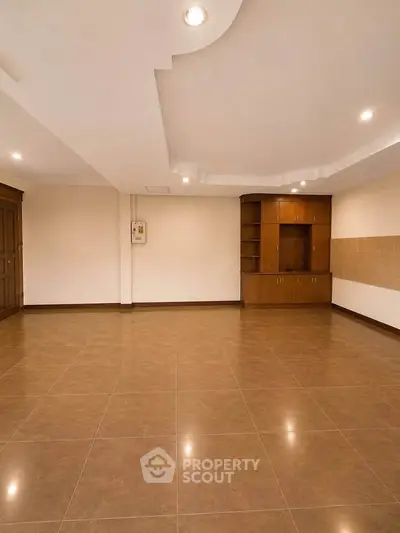 Spacious empty room with tiled flooring and built-in wooden cabinets, ideal for customization.