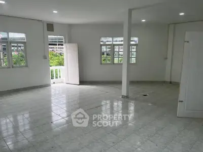 Spacious empty room with tiled flooring and large windows offering natural light.