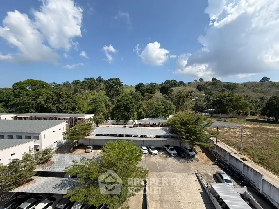 Scenic view of residential complex with lush greenery and spacious parking area under a clear blue sky.