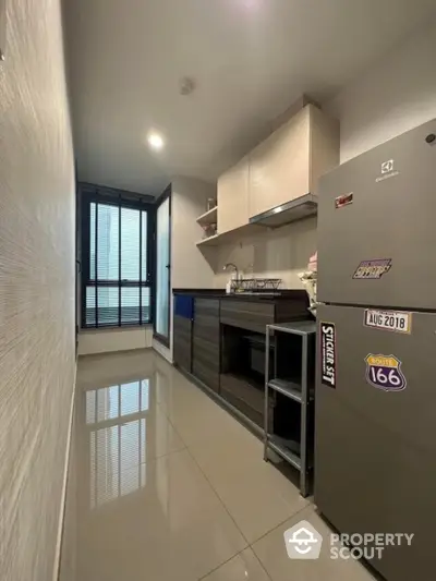 Modern kitchen with sleek cabinets and stainless steel fridge in compact layout