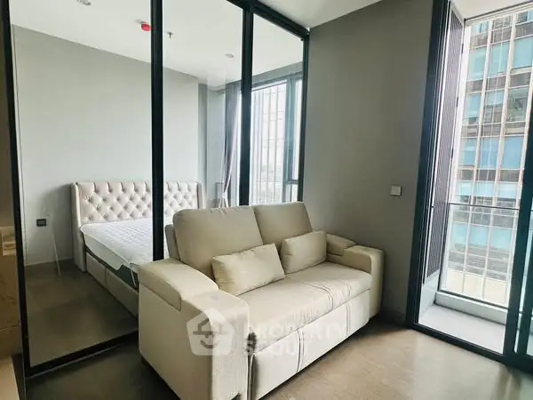 Modern bedroom with mirrored closet and cozy sofa near balcony view