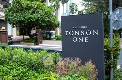 Elegant entrance of Tonson One Residence surrounded by lush greenery, showcasing modern urban living.