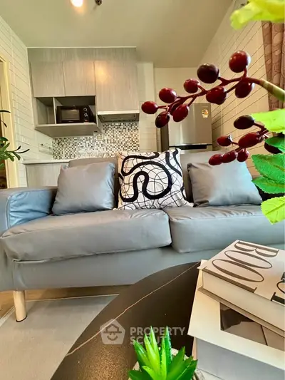 Modern living room with stylish decor and open kitchen layout, featuring sleek appliances and cozy seating.