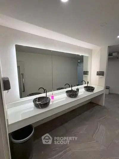 Modern bathroom with dual black sinks and large mirror in sleek design.
