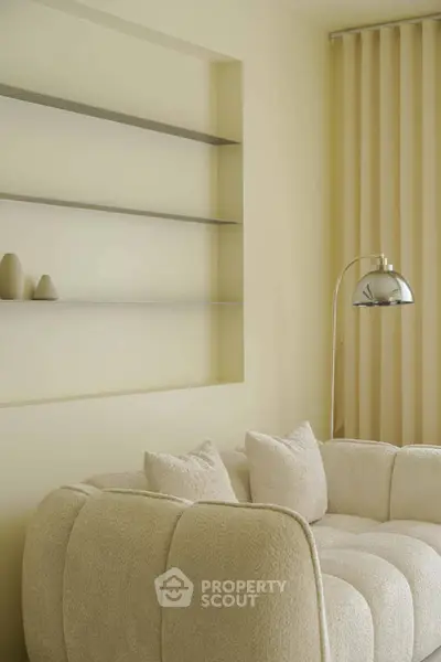 Elegant living room with plush beige sofa and modern floor lamp, perfect for cozy relaxation.