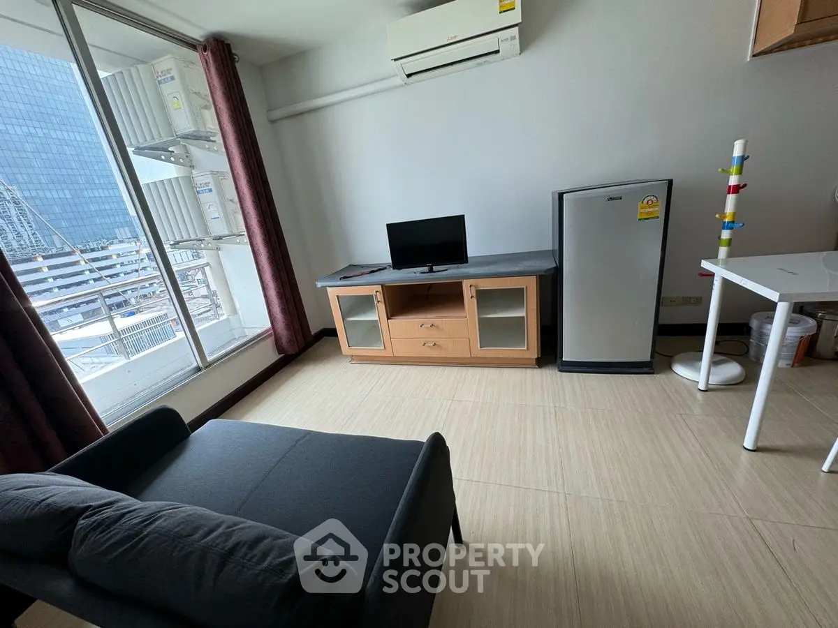 Modern living room with balcony view, compact furniture, and sleek design in urban apartment.