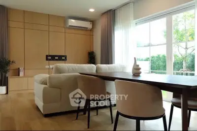 Modern living room with elegant furniture and large window overlooking garden