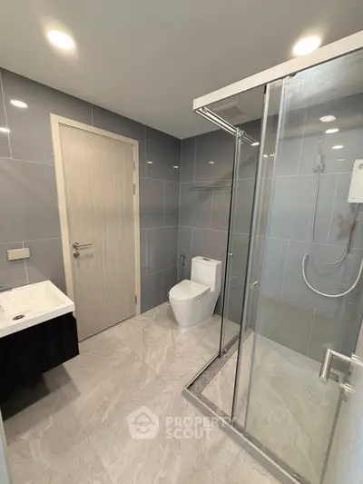 Modern bathroom with sleek design, featuring a glass shower enclosure and elegant fixtures.