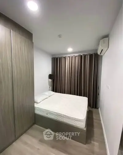 Modern bedroom with sleek design, featuring a comfortable bed, stylish wardrobe, and air conditioning.