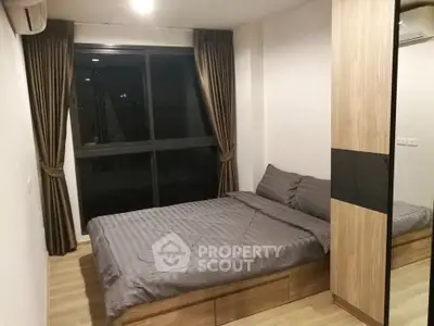 Modern bedroom with large window and stylish wooden wardrobe in a cozy apartment.