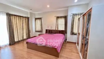 Spacious bedroom with wooden flooring and ample natural light