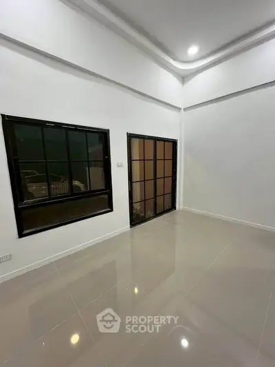Spacious empty room with large windows and glossy tiled floor, perfect for customization.