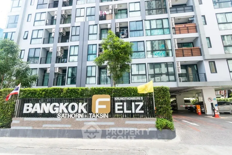 Modern Bangkok condo exterior with lush greenery and secure parking.