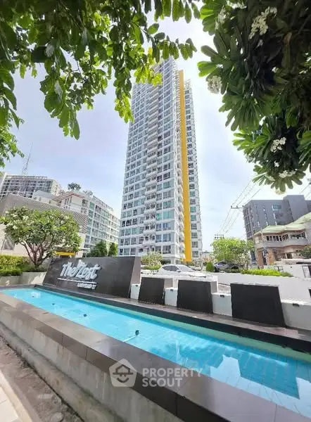 Modern high-rise condominium with lush landscaping and sleek design in urban setting.