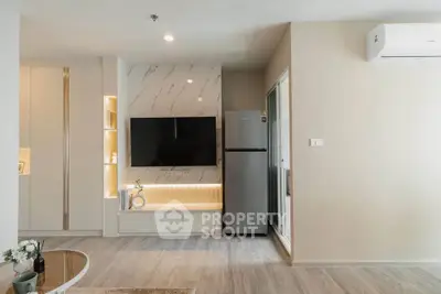 Modern living room with sleek design, featuring a wall-mounted TV, stylish cabinetry, and a stainless steel fridge.