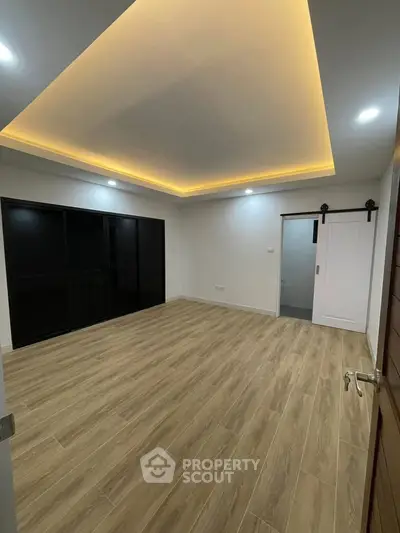 Spacious modern room with wooden flooring and recessed lighting