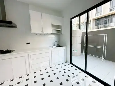 Modern kitchen with sleek design and outdoor access, featuring tiled floors and ample natural light.