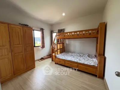 Spacious bedroom with wooden bunk bed and wardrobe, perfect for family living.