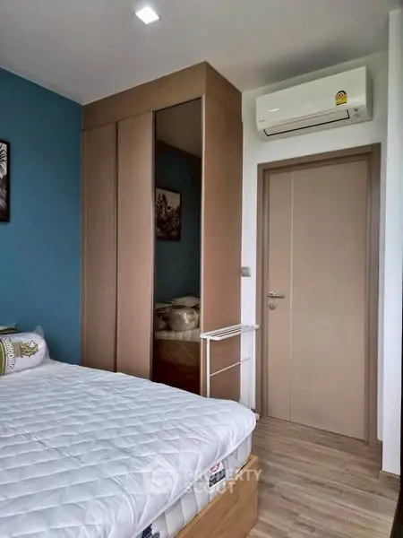 Cozy bedroom with modern design, featuring a comfortable bed, sleek wardrobe, and air conditioning.