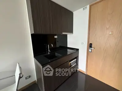 Modern compact kitchen with sleek dark cabinetry and built-in appliances