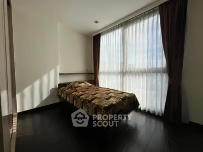 Cozy bedroom with large window and elegant curtains, featuring a comfortable bed and wooden flooring.