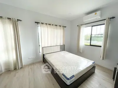 Spacious bedroom with large windows allowing ample natural light, featuring air conditioning and elegant floor tiling, perfect for restful living.