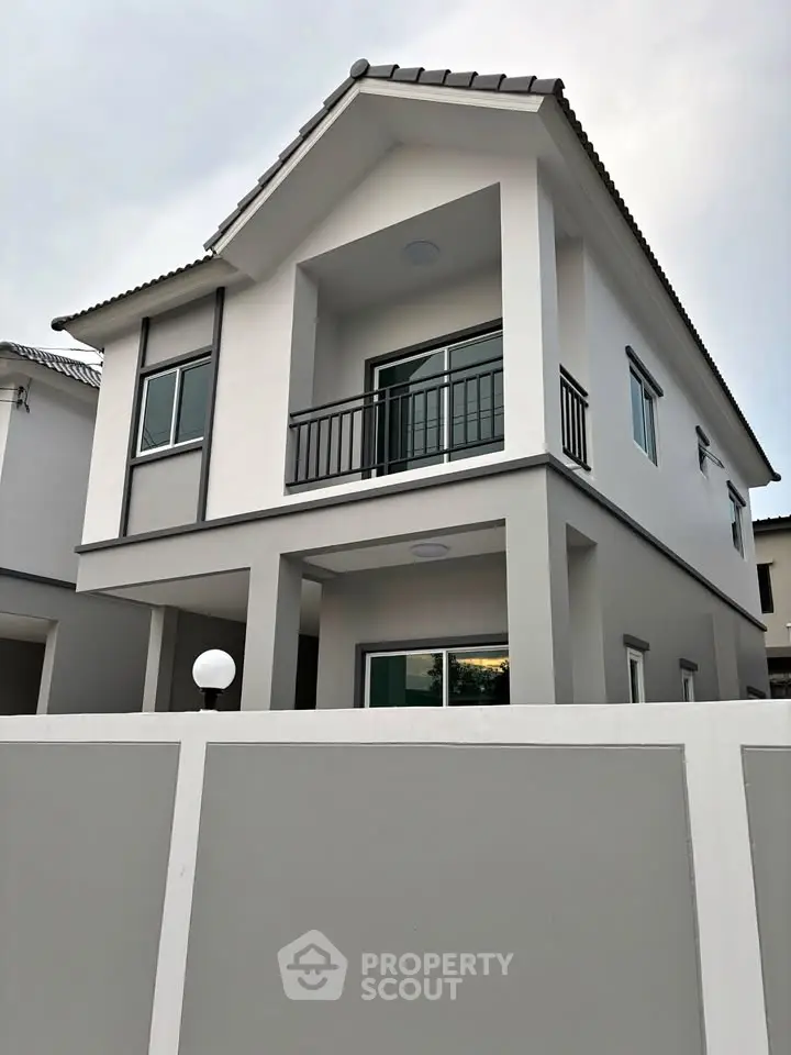 Modern two-story house with balcony and sleek design, perfect for family living in a serene neighborhood.