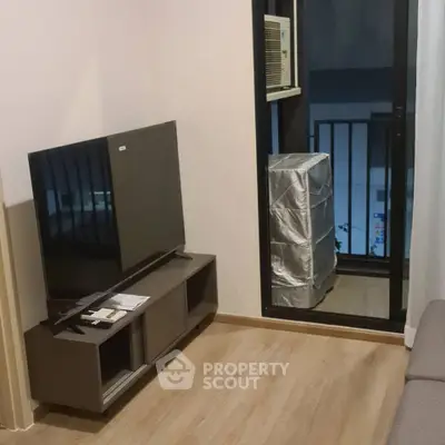 Cozy living room with modern TV setup and balcony access, perfect for urban living.