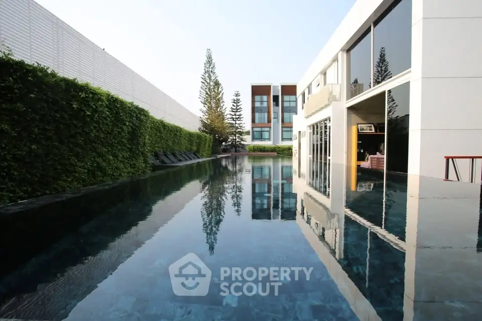 Luxurious modern building with stunning pool and lush greenery, perfect for relaxation and leisure.