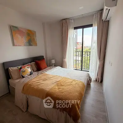 Cozy bedroom with modern decor and large window offering natural light and a view.