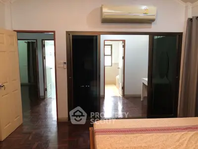 Spacious bedroom with ensuite bathroom and air conditioning, featuring elegant wooden flooring.