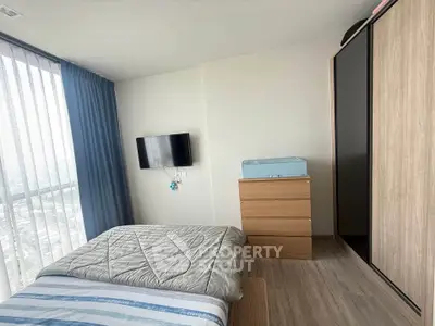 Modern bedroom with large window, stylish wardrobe, and mounted TV, offering a cozy and bright living space.