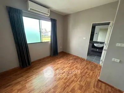 Spacious bedroom with wooden flooring and en-suite bathroom in modern apartment.
