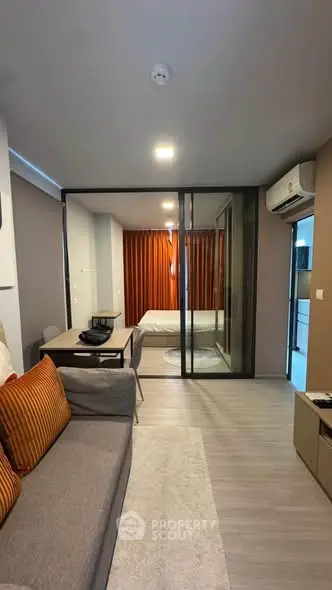 Modern apartment interior with open layout, featuring a cozy living area and a glimpse of the bedroom.