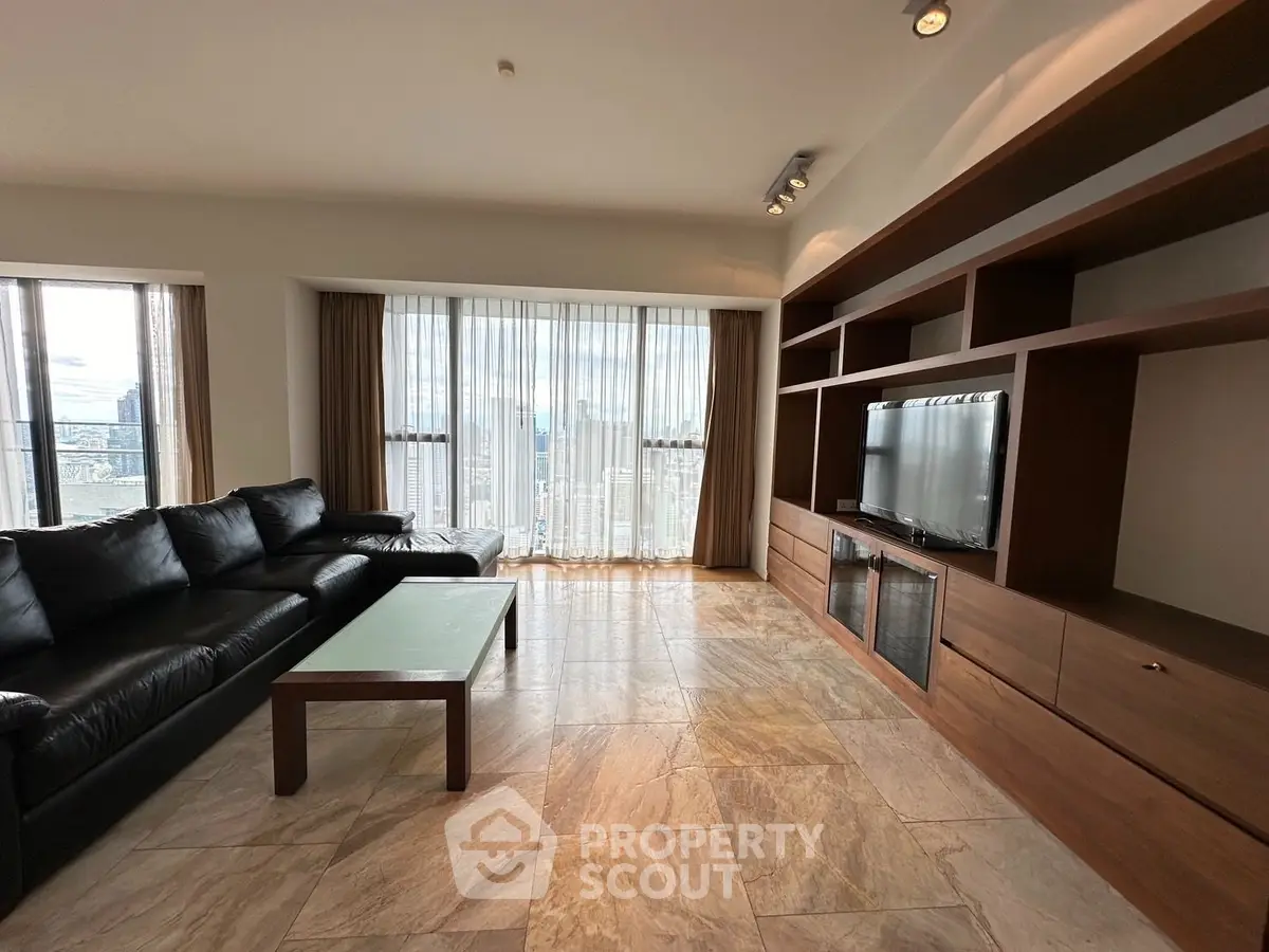 Spacious living room with modern furniture and large windows offering a stunning city view.