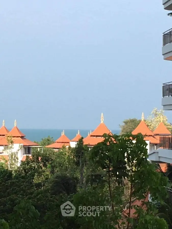 Stunning ocean view from a luxurious resort balcony with lush greenery and traditional architecture.