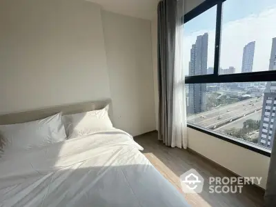 Modern bedroom with city view and large window in high-rise apartment