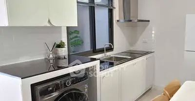 Modern kitchen with sleek appliances and washing machine, featuring a minimalist design and ample counter space.
