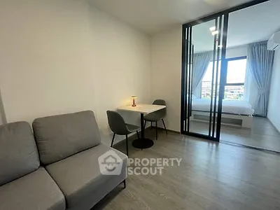 Modern studio apartment with cozy living area and bedroom separated by glass partition.