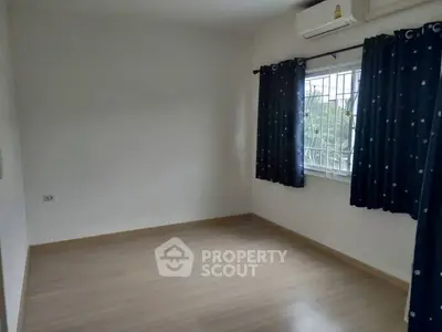 Spacious empty bedroom with wooden flooring and large window