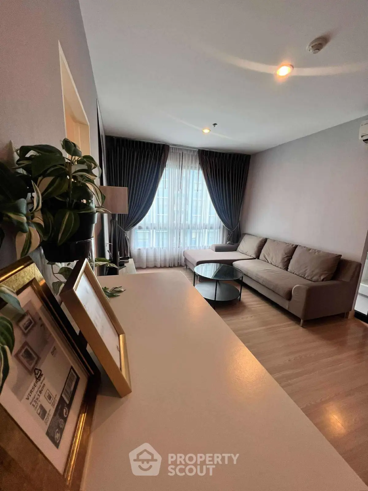 Modern living room with cozy sofa and elegant decor, featuring large window and stylish curtains.