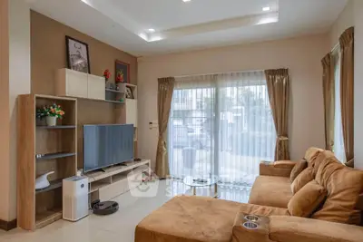 Spacious living room with modern decor, large TV, and comfortable seating in a bright, airy space.