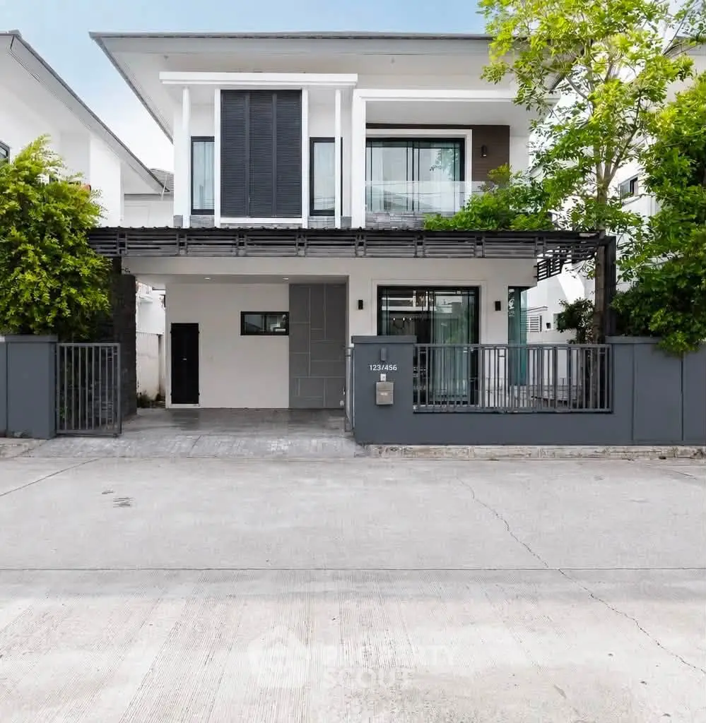 Modern two-story house with sleek design and lush greenery in a serene neighborhood.