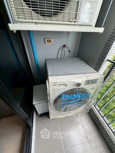 Compact balcony with washing machine and air conditioning unit in modern apartment.