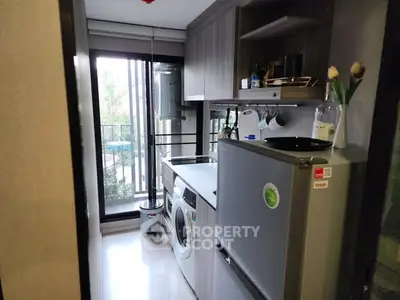Modern kitchen with washing machine and fridge, featuring sleek cabinetry and balcony view.